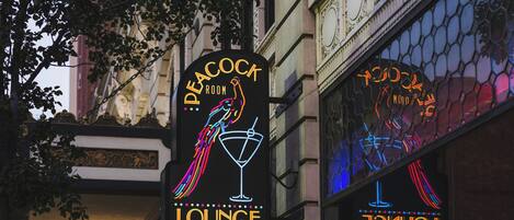 A neon sign for Peacock Lounge with a peacock and cocktail glass.