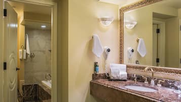 A bathroom with a marble sink, a large mirror, and a hairdryer on the wall.