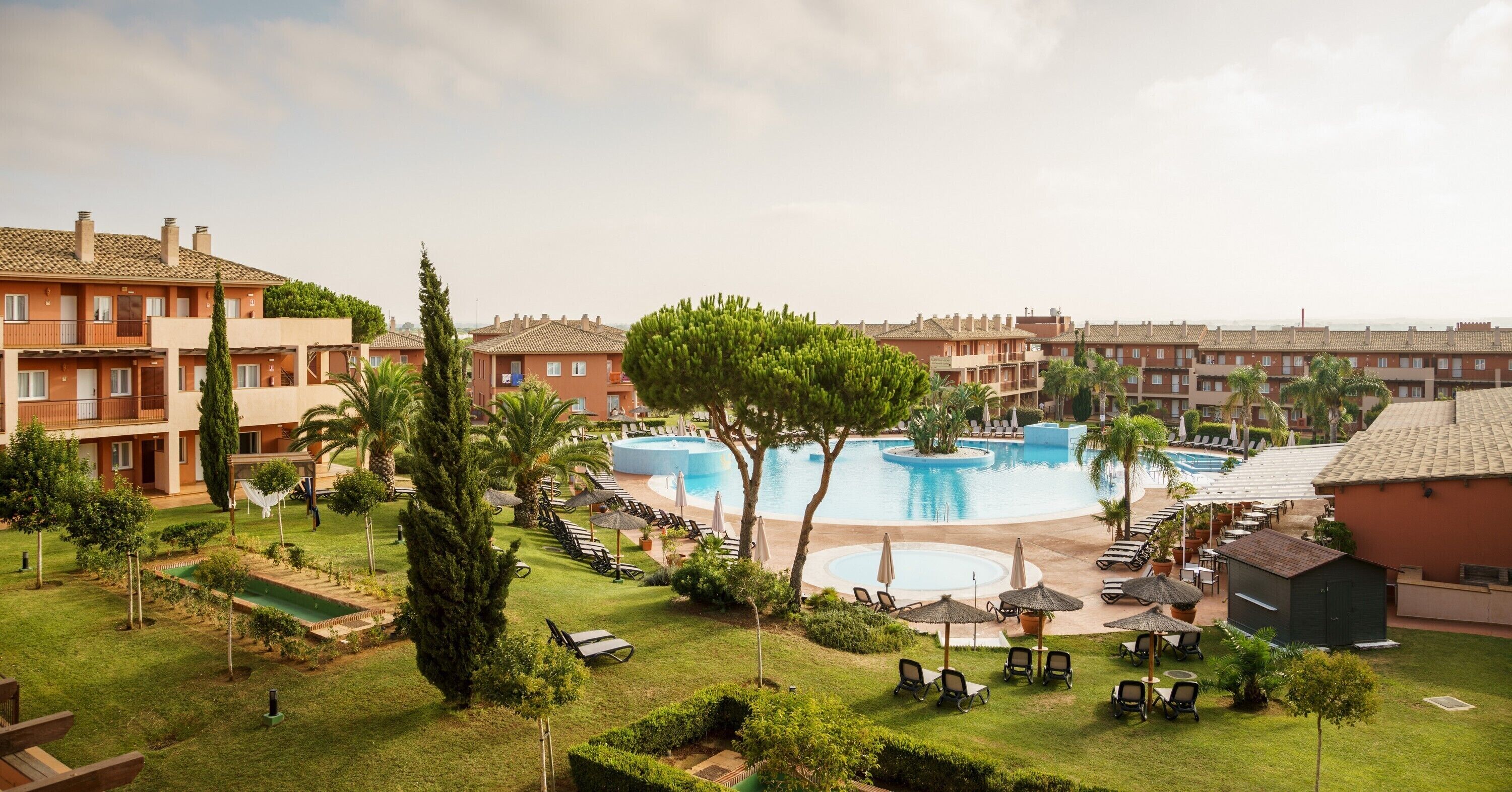 Un hotel con piscina, mobiliario exterior y un jardín bien cuidado.