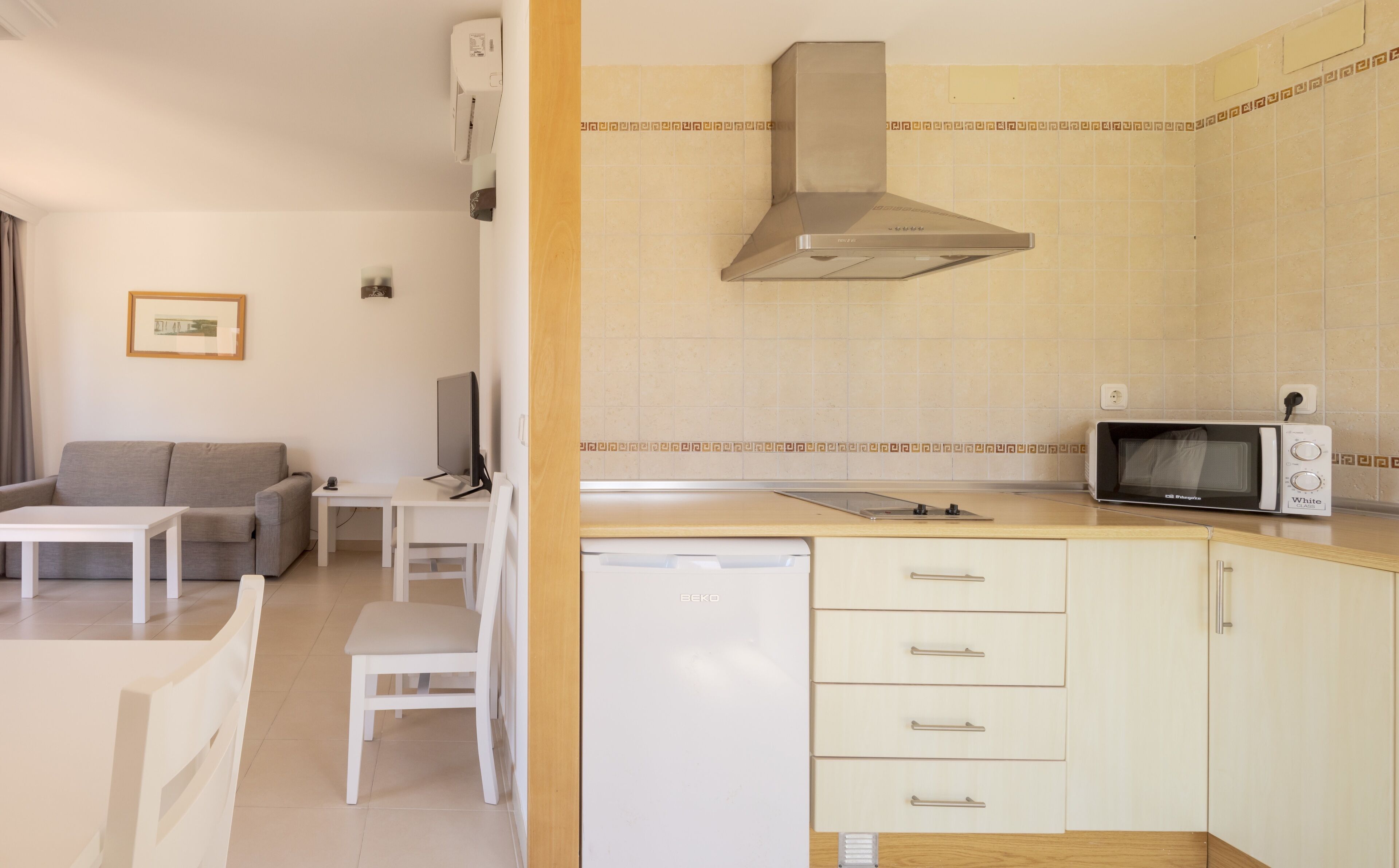 Cocina compacta con microondas, pileta y estufa. Hay un comedor con mesa y sillas.