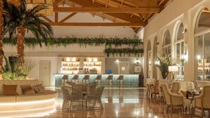 A spacious lobby with a bar area, seating arrangements, and a palm tree.