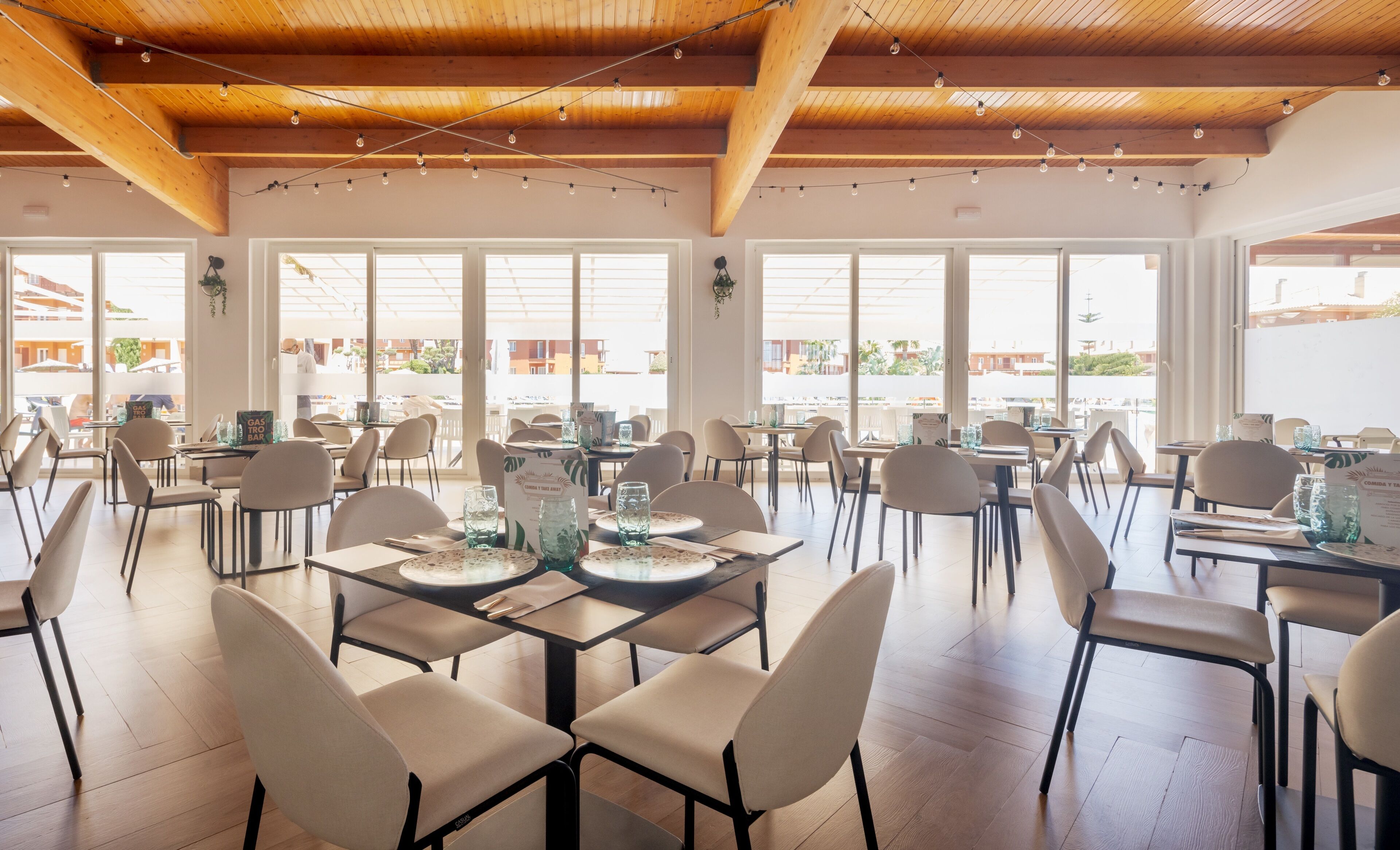 A spacious dining area with high ceilings and large windows, featuring modern furniture and a clean, bright atmosphere.