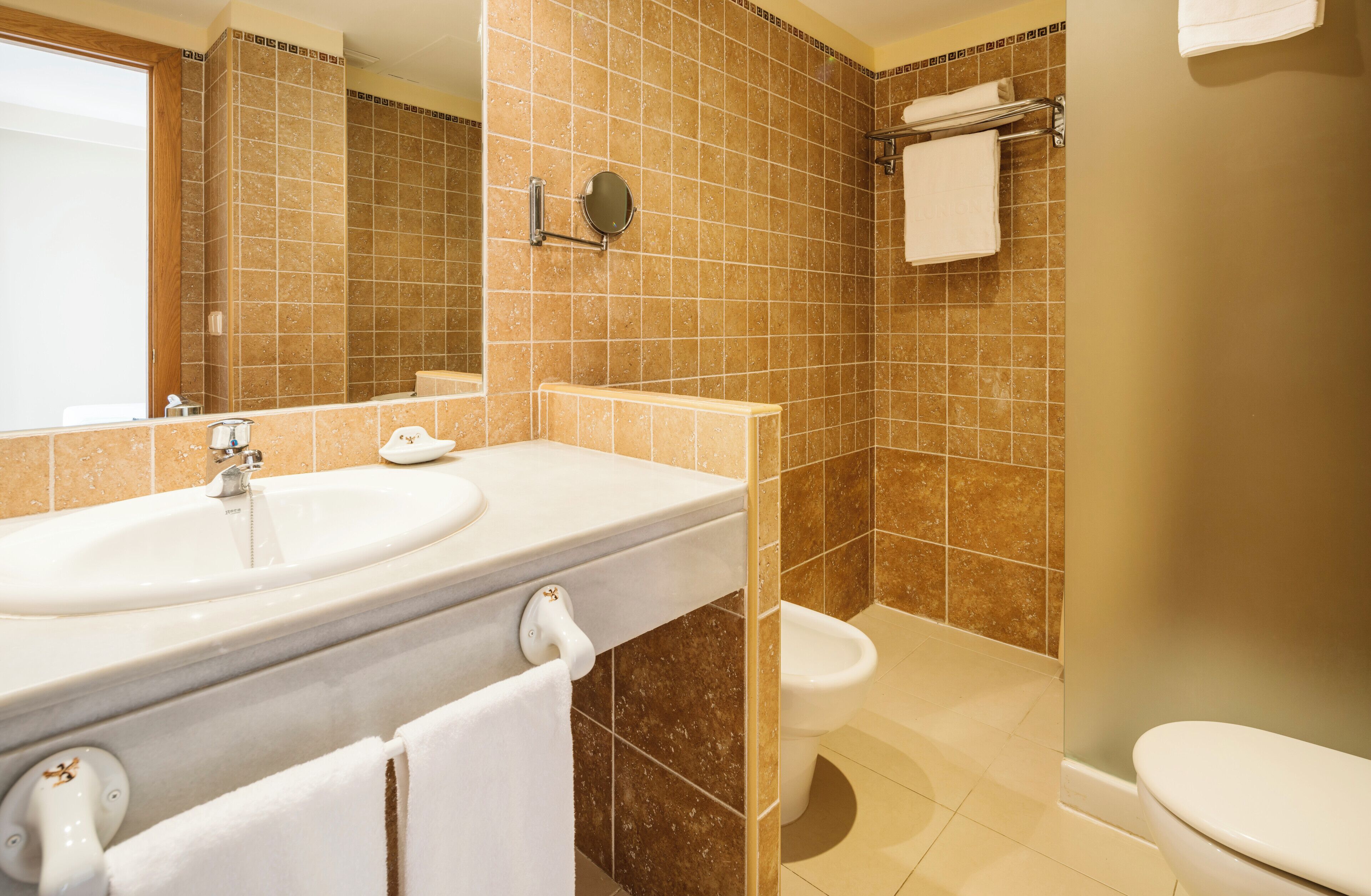 A bathroom with a sink, mirror, toilet, and shower.