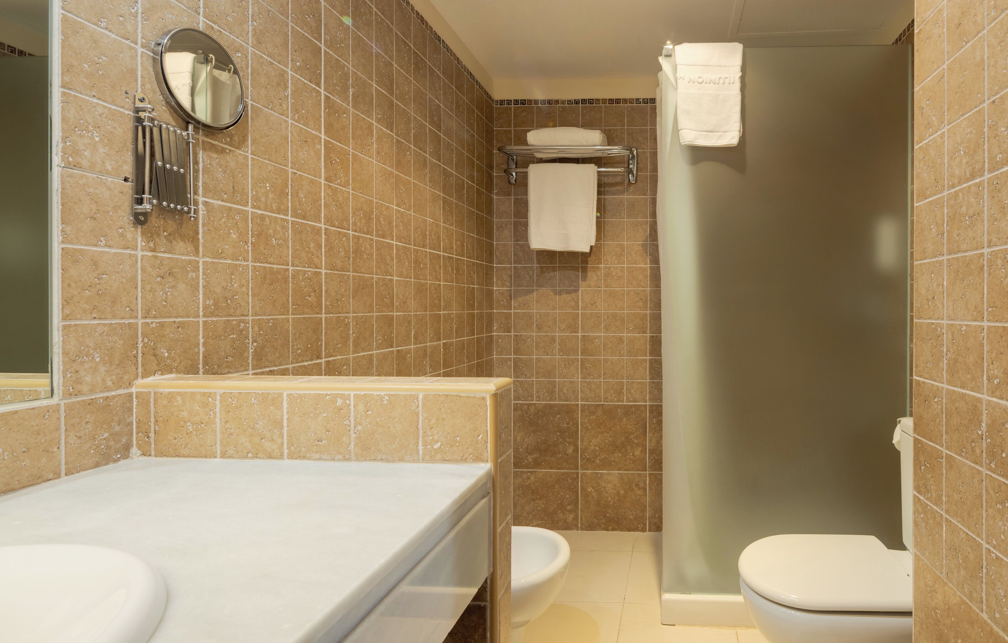 A bathroom with a shower, toilet, sink, and a towel rack.