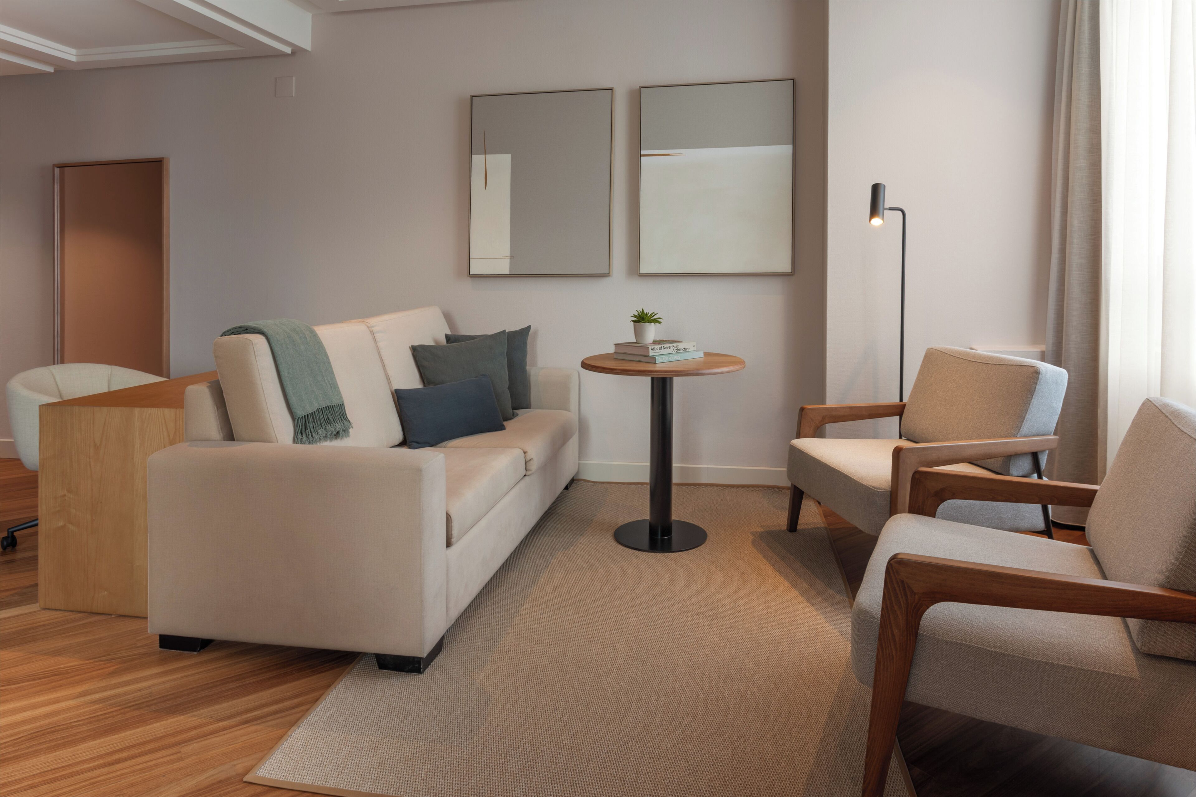 A modern living room with a sofa, armchairs, a coffee table, and a floor lamp.