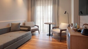 Una sala de estar moderna con un sofá, dos sillones, una mesa redonda de centro y un televisor de pantalla plana montado en la pared.