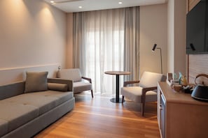 Ein modernes Wohnzimmer mit einer Couch, zwei Sesseln, einem runden Couchtisch und einem flachbildfernseher, der an der Wand montiert ist.
