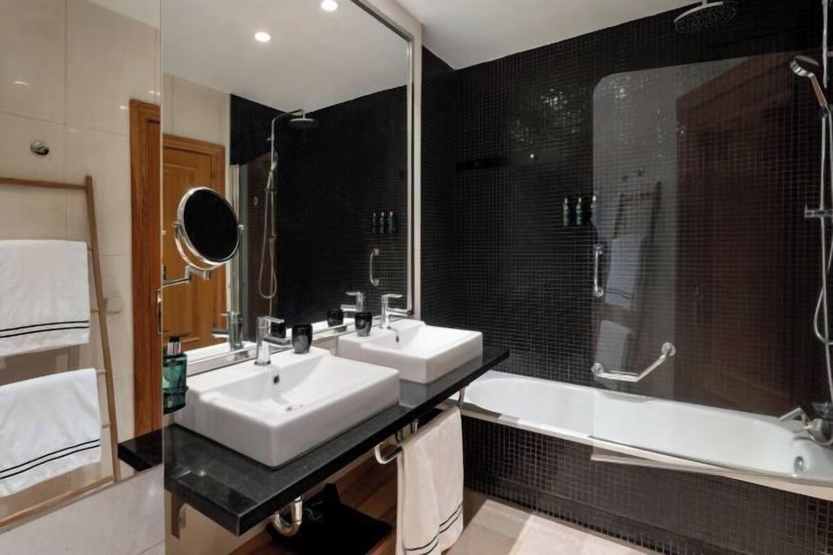 Ein modernes Badezimmer mit zwei Waschbecken, einem großen Spiegel, einer Dusche und einer Badewanne.