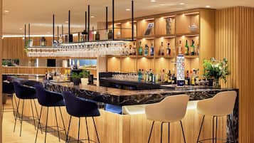 A bar area with a marble countertop, multiple bar stools, and a variety of bottles and glasses.