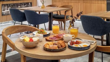 A breakfast setting with a variety of food items, including eggs, pastries, and fruit, on a wooden table.