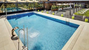 Una piscina al aire libre de temporada, sombrillas, tumbonas