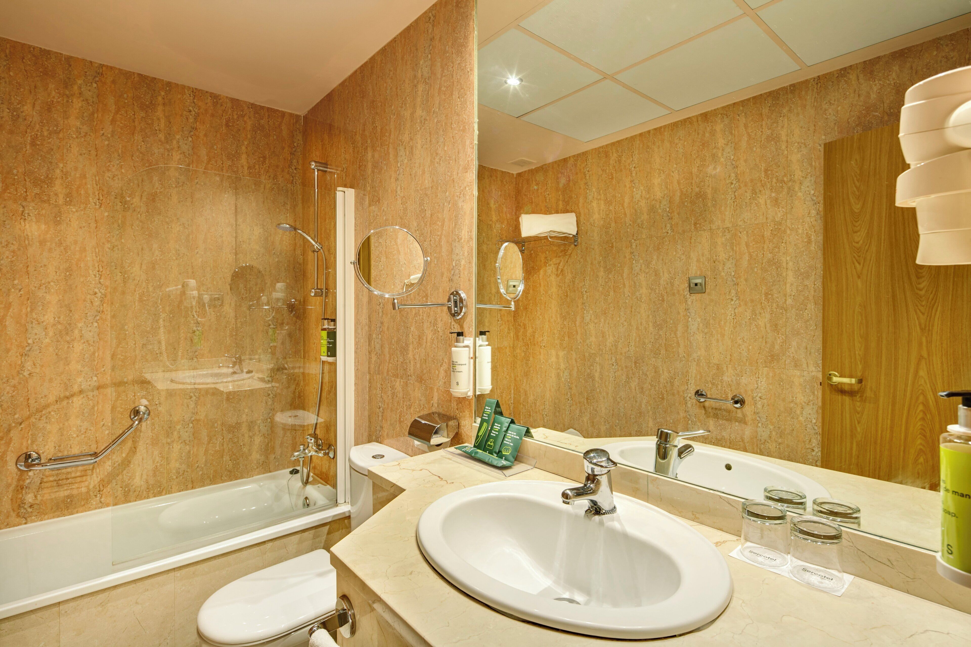A bathroom with a bathtub, a sink, a mirror, and toiletries.