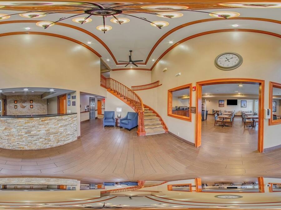 A spacious lobby with a central staircase, a reception desk, and a dining area.