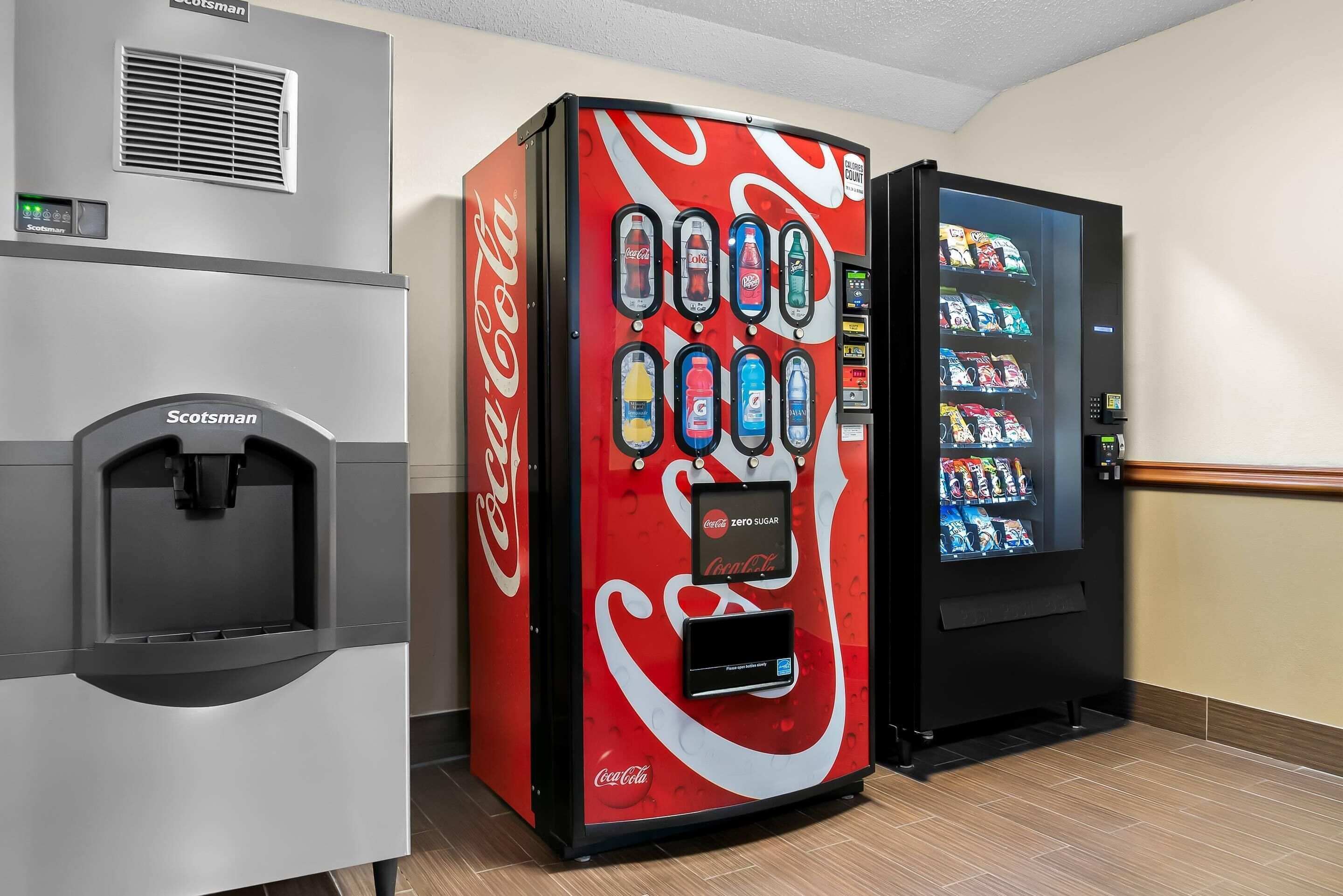 Una máquina expendedora con el logotipo de Coca-Cola, un dispensador de agua y una máquina expendedora de aperitivos.