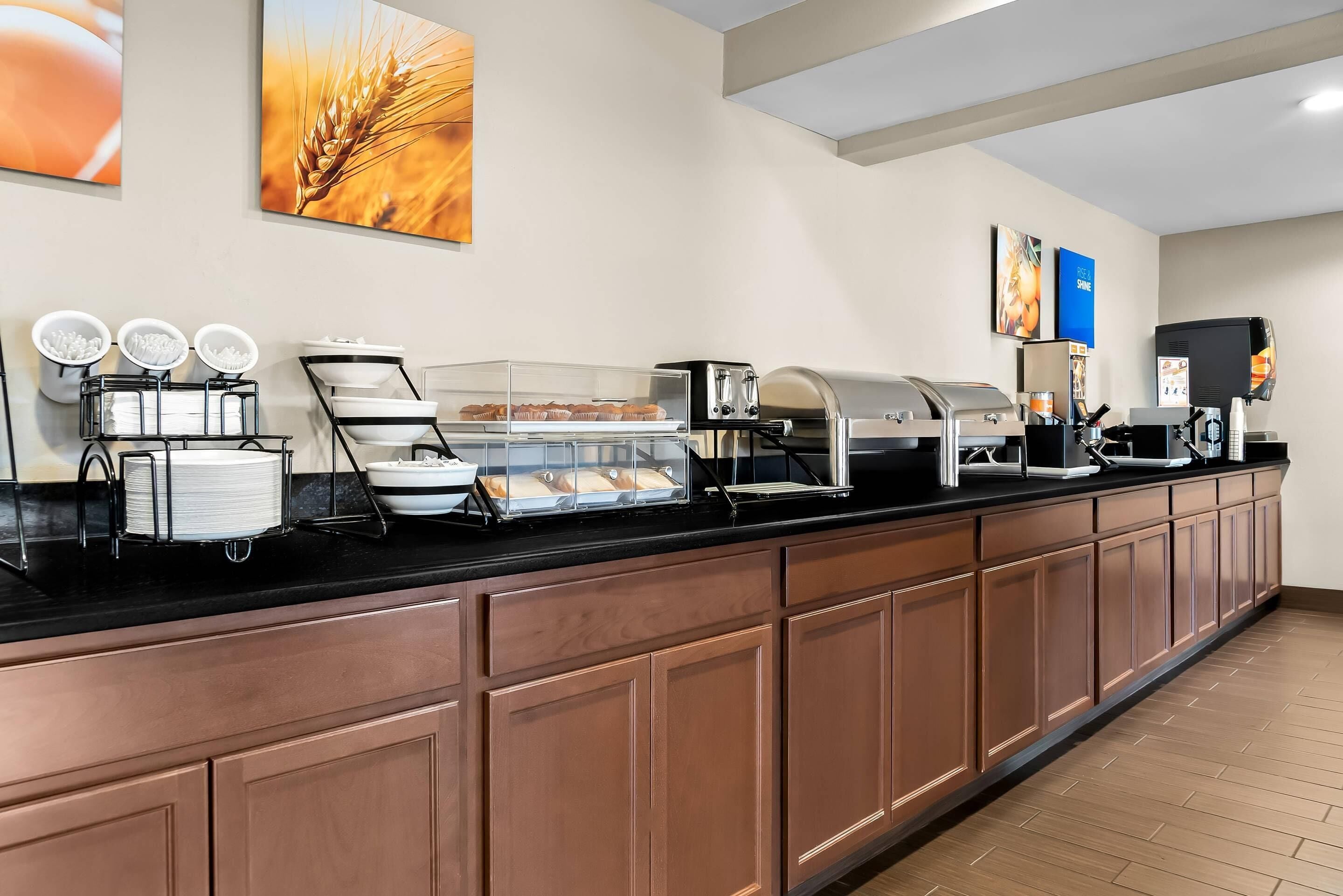 A buffet counter with various food stations, including a cereal bar, a coffee station, and a display case with pastries.