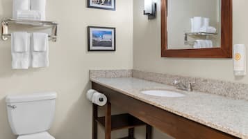 A bathroom with a toilet, sink, towel rack, and framed pictures on the wall.