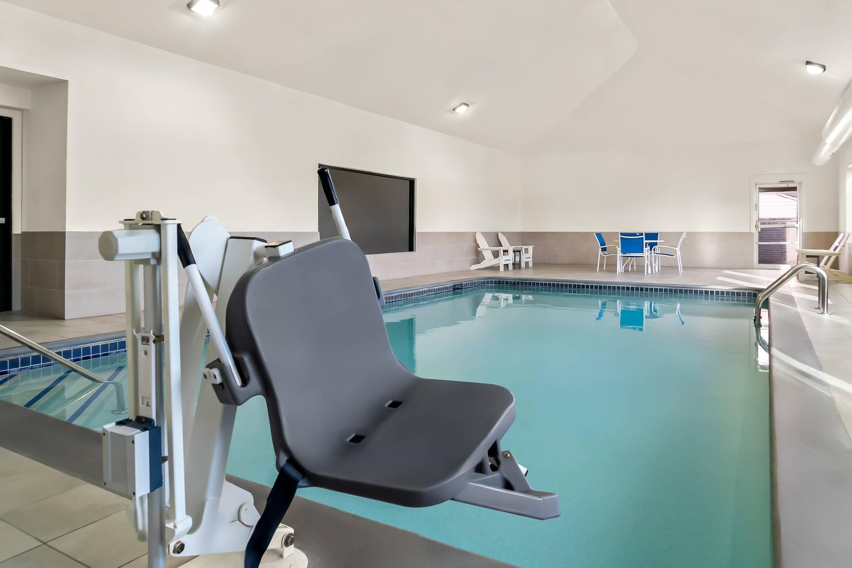 Une piscine intérieure équipée d’un fauteuil, d’un écran de télévision et de quelques chaises disposées autour de la piscine.