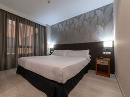 Una habitación de hotel con una cama grande, una mesita de noche y una pared con diseño de mariposas.