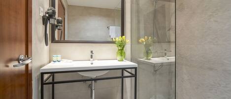 A modern bathroom with a glass-enclosed shower, a white sink with a black frame, and a large mirror above the sink.