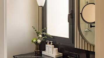 A modern bathroom with a large mirror, a round mirror, a black countertop, a white sink, and a pendant light.