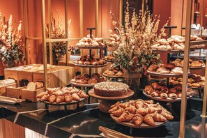 A bakery display with various pastries and bread, arranged on wooden stands and tables. - Casa de Las Artes, member of Meliá Collection (Madrid)