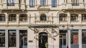 Un edificio de varios pisos con estilo arquitectónico clásico, que presenta ventanas simétricas y elementos decorativos alrededor de la entrada.