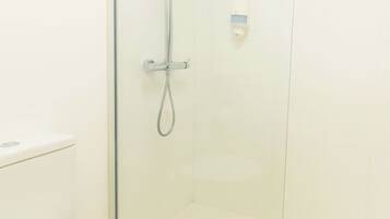 Ein modernes Badezimmer mit einer Glaskabine zur Dusche, einer weißen Toilette und einem Holzboden.