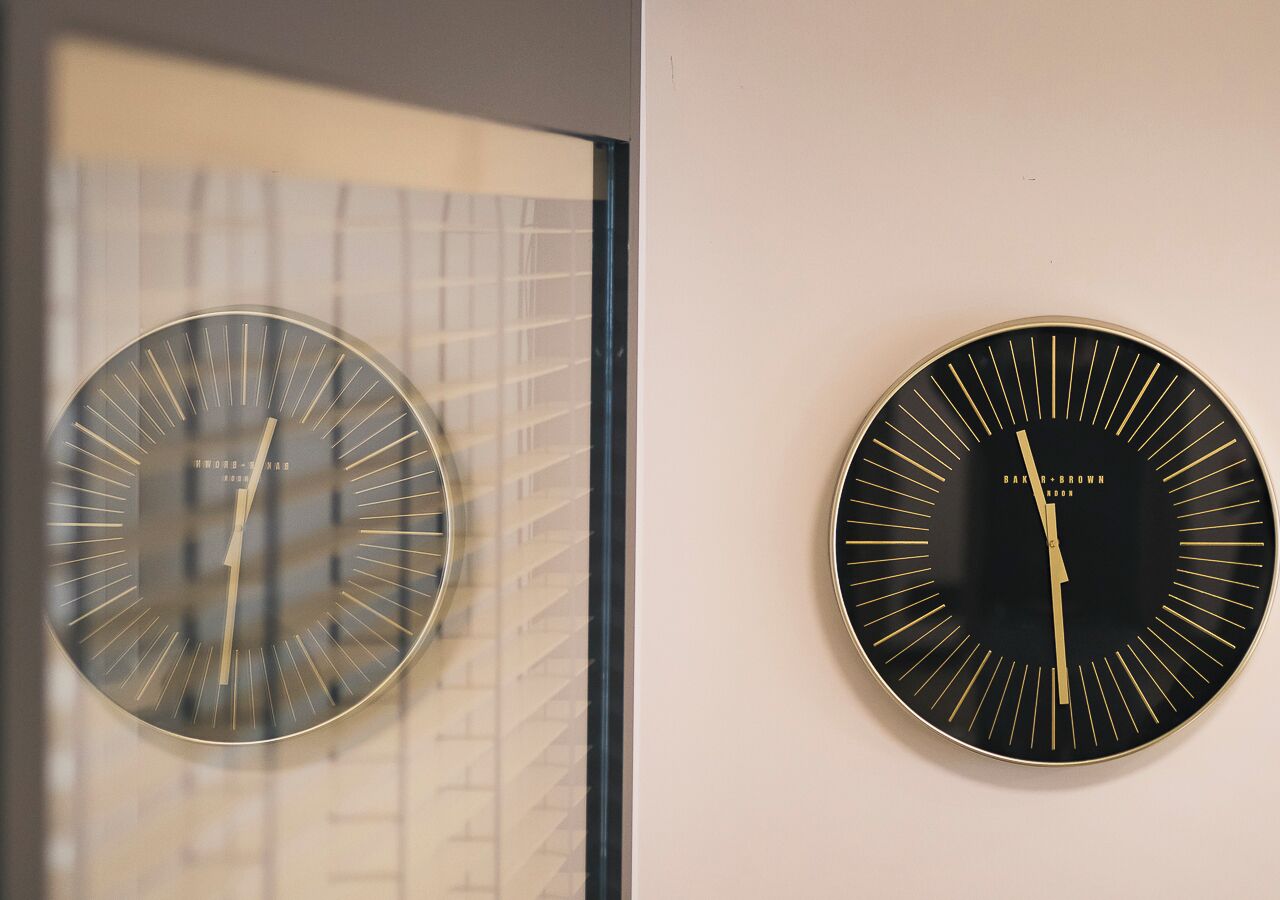 Two wall-mounted clocks with a modern design, one with a grid pattern and the other with radial lines.