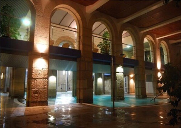Ein Innenhof mit Steinsäulen, einem offenen Mittelbereich und einem Pool.