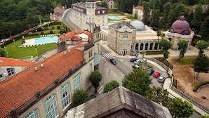 A historic building with classical architecture, including domed structures and arched windows, surrounded by a landscaped garden and a swimming pool. - Balneario de Mondariz (Mondariz-Balneario)
