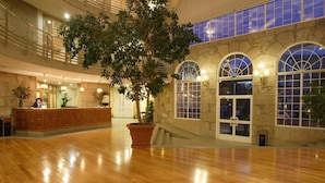 A spacious lobby with a wooden floor, a reception desk, and a large potted tree. - Balneario de Mondariz (Mondariz-Balneario)