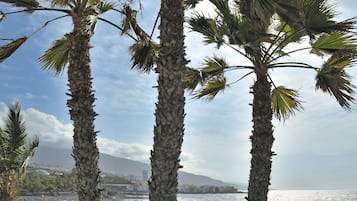 Arena negra, sillas reclinables de playa, sombrillas