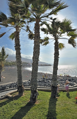 In Strandnähe, schwarzer Sandstrand, Liegestühle, Sonnenschirme