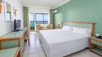 Hotelkamer met een groot bed, een bureau met stoel, een televisie en uitzicht op zee.