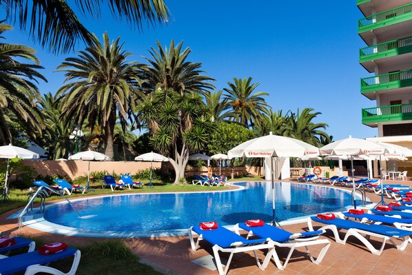 Una piscina al aire libre, sombrillas, sillones reclinables de piscina