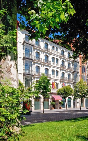 Un edificio de varios pisos con balcones, un patio interior y banderas.
