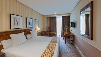 Una habitación de hotel con una cama grande, un escritorio, una silla y un televisor.