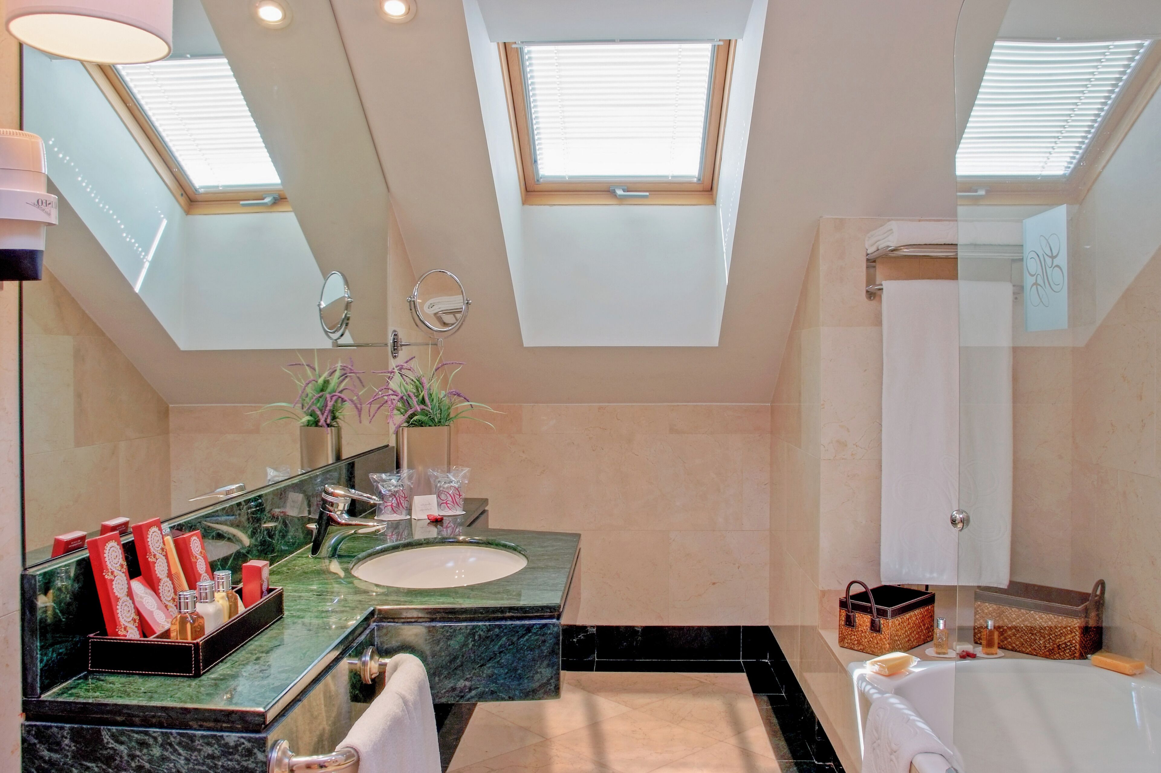 A modern bathroom with skylights, a large mirror, a sink, and a bathtub.