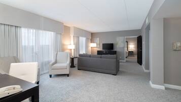 A hotel room with a sofa, armchair, and a small table with a telephone.