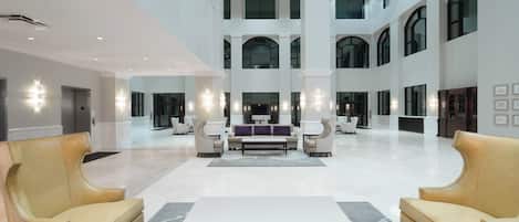 Un hall espacioso con techos altos, varias zonas de estar y luminarias modernas.