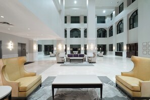 A spacious lobby with high ceilings, multiple seating areas, and modern lighting fixtures. - Holiday Inn Wilmington by IHG (Wilmington)