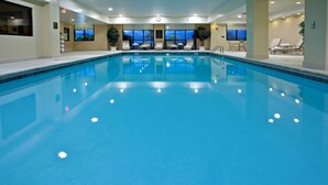 A large indoor swimming pool with clear blue water, surrounded by lounge chairs and tables. - Holiday Inn Wilmington by IHG (Wilmington)