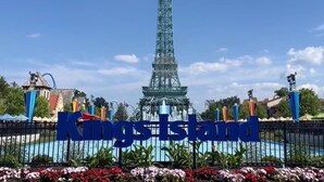 A sign with "Kings Island" written in large blue letters, a replica of the Eiffel Tower in the background, and a fence with colorful flags. - Holiday Inn Wilmington by IHG (Wilmington)