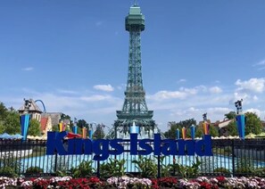 A sign with "Kings Island" written in large blue letters, a replica of the Eiffel Tower in the background, and a fence with colorful flags. - Holiday Inn Wilmington by IHG (Wilmington)