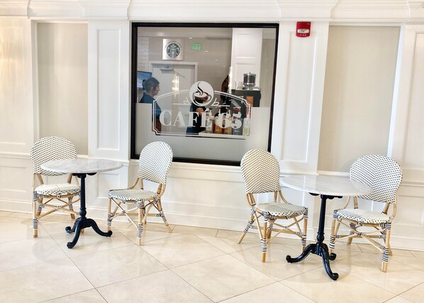 A seating area with four chairs and two tables, a Starbucks sign, and a fire alarm. - Holiday Inn Wilmington by IHG (Wilmington)
