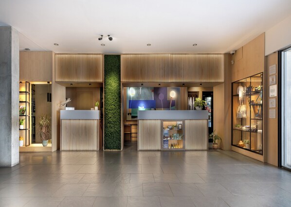 Un espace d’accueil moderne agrémenté d’un mur végétal central, de lambris en bois et d’une vitrine.