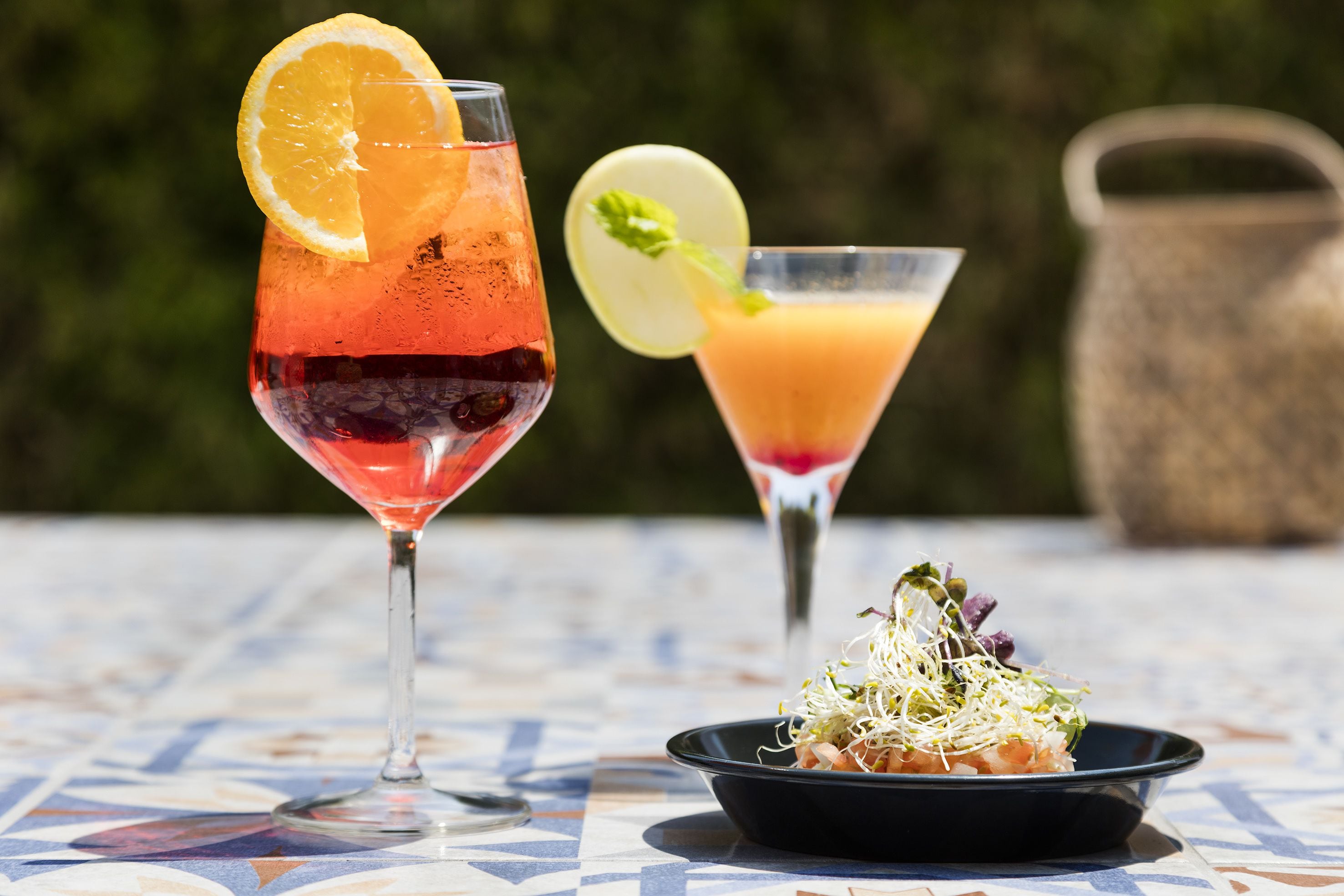 Two cocktails on a tiled table with a salad.