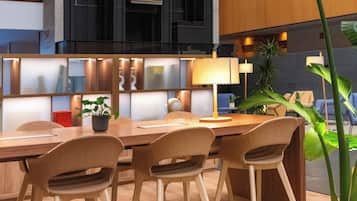 Una sala de reuniones moderna con una mesa larga, cuatro sillas, una planta en maceta y un amplio ventanal con vistas al interior del edificio.
