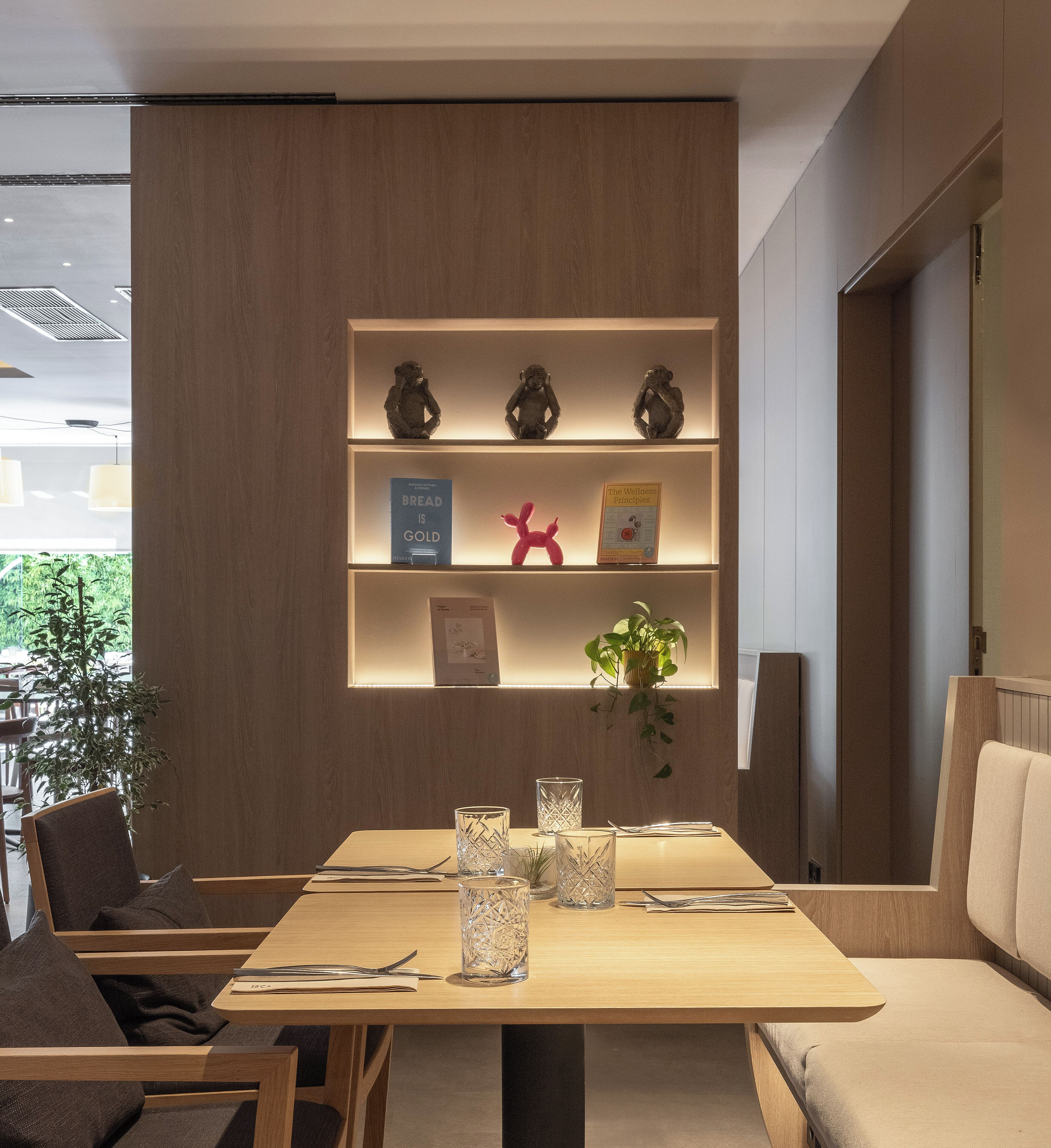 Un comedor moderno con una mesa de madera, sillas y una estantería con libros y objetos decorativos.