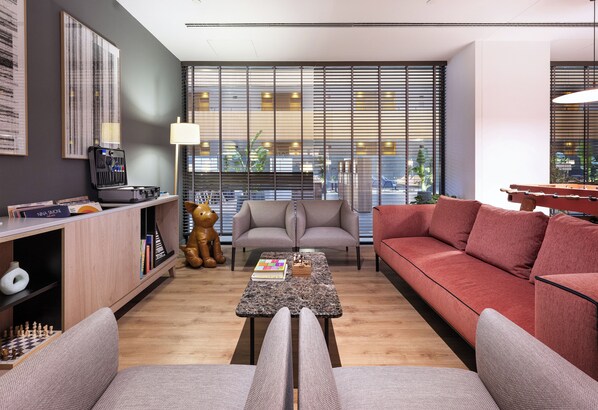 A modern living room with a sofa, armchairs, a coffee table, and a bookshelf.